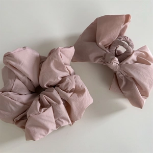 Detail of rose pink fabric scrunchie and large bow hair claw clip set on white background