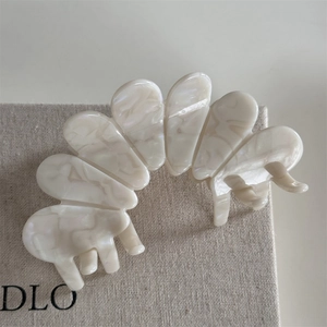 Detailed close-up of a cream acetate hair claw with elegant marble texture and pearl luster