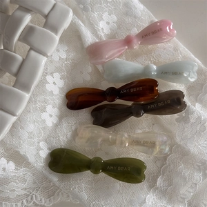 Détail de barrettes à cheveux nœud en acétate coloré sur tissu en dentelle blanche