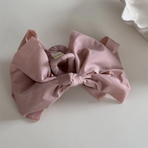 Detail view of large pink fabric bow claw clip with elegant cotton-linen texture