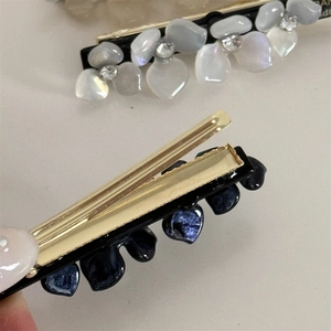 Macro detail of acetate flower hair clips with rhinestones in grey and blue colors