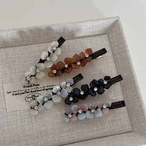Detailed macro view of five colorful acetate flower hair clips with rhinestones and gold text