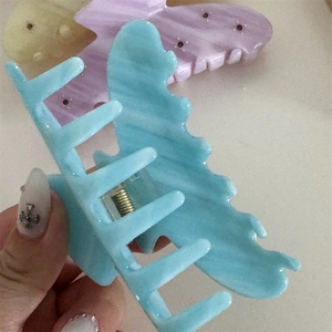 Detail of blue acetate claw clip with marble texture and sturdy golden metal spring