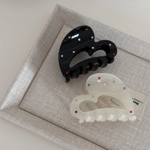 Detail of heart hair claws in black and cream with colorful rhinestones on fabric tray