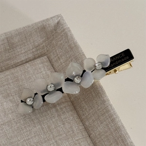 Close-up of floral acetate hair clip with rhinestones and France Handmade gold metal detail