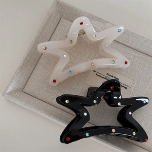 Detailed close-up of star-shaped hair claw clips with colorful rhinestones in cream and black