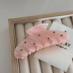 Detail of pink acetate shark hair claw with rhinestones on velvet jewelry box