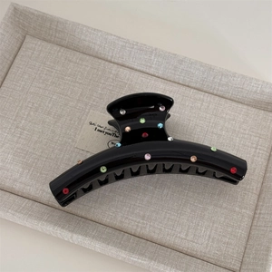 Close-up of black glossy hair claw clip featuring colorful sparkling rhinestones and fine teeth