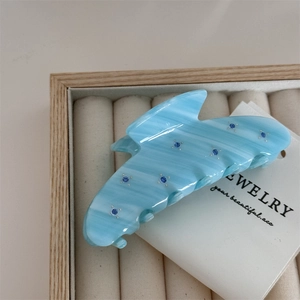 Macro view of blue marble acetate hair claw clip with rhinestones in a velvet jewelry box