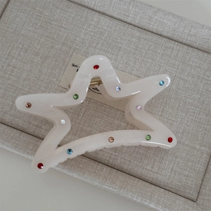 Detailed close-up of a star-shaped acrylic hair claw with colorful rhinestones and gold spring