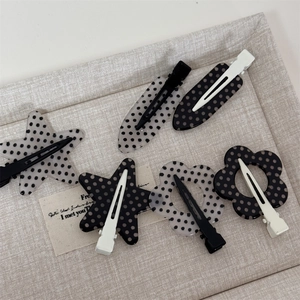 Polka dot hair clip set in star and flower shapes on a textured fabric background