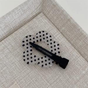 Detailed view of a sweet floral hair clip with black polka dots on a translucent finish