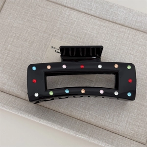 Macro shot of rectangular black hair claw clip decorated with colorful rhinestones