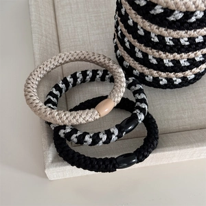 Set of thick braided elastic hair ties in beige and black displayed on a fabric tray