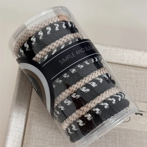 Macro detail of braided high-elastic hair ties in a clear minimalist storage jar