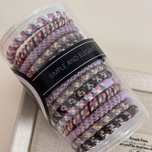 Detail view of woven high-elastic hair ties in a clear cylinder box with elegant labeling