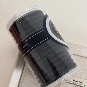 Close-up of 15 black braided elastic hair bands stored in a clear cylindrical container