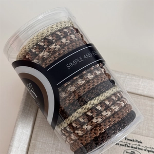 Detail of woven high-elasticity hair ties in brown and beige colors inside a clear tube