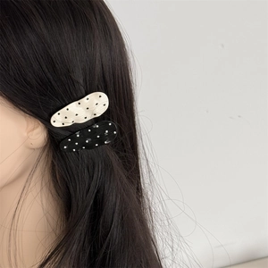 Detail of polka dot wave hair clips in black and white on long dark hair