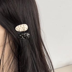 Polka dot hair clip set in black and white on long dark hair, elegant wavy design