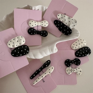 Detail view of assorted black and white polka dot hair clips on a pink card