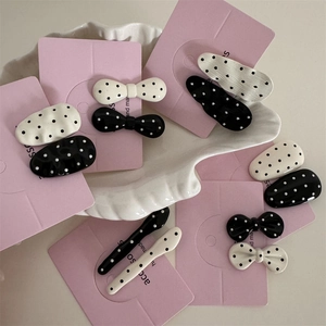 Chic black and white polka dot hair clip set with elegant metal bow accents on pink cards