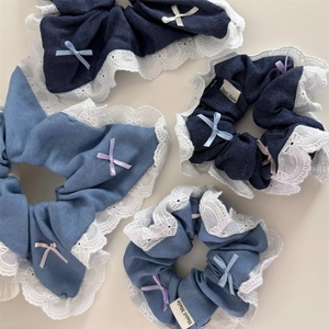 Macro detail of denim scrunchies with white lace edges and colorful ribbon bows
