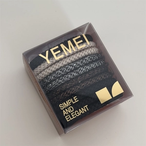 Detail of high-elasticity hair ties in a clear box featuring black and beige tones