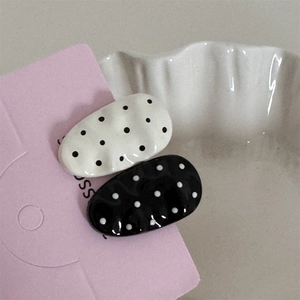 Close-up of black and white polka dot hair clips with glossy wavy oval design on a card
