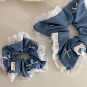 Detailed close-up of blue denim scrunchies with white lace edges and small colorful bows