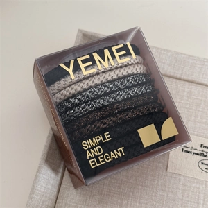 Close-up of elegant elastic hair ties in neutral tones within a premium branded gift box