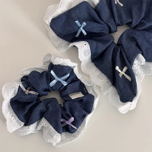 Detailed macro view of denim scrunchies with white lace trim and colorful bow accents