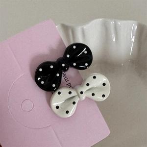 Macro detail of classic black and white polka dot bow hair clips with glossy enamel finish