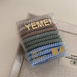 Close-up of 10-piece elastic hair ties set in earthy and forest green tones in a clear box