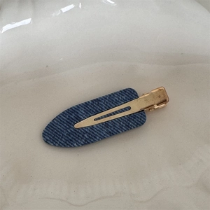 Detail view of denim texture hair clip on a minimalist wavy ceramic decorative tray
