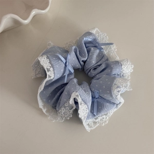 Vue détaillée du chouchou bleu clair à pois avec bordure en dentelle et nœuds doux