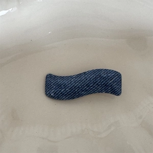 Detail showing the denim twill fabric texture and wavy shape of this stylish hair clip
