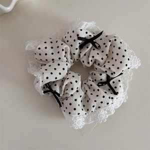Détail d'un chouchou blanc à pois avec bords en dentelle et petits nœuds noirs