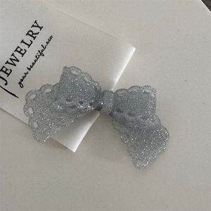 Detail einer grauen Glitzer-Haarschleife mit Spitzenrand und funkelndem Finish