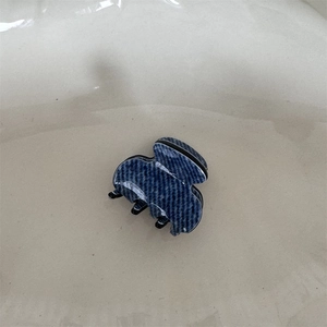 Close-up of mini acetate hair claw with blue and white woven texture for hair styling