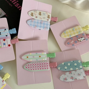 Macaron color duckbill hair clips with floral and polka dot patterns on pink cardboards