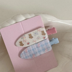 Detail of floral and bear pattern hair clips on display card with matte finish