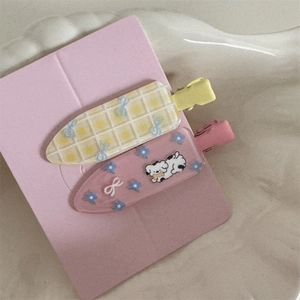 Detail of floral and checkered duckbill hair clips with a cute cartoon dog and blue bows