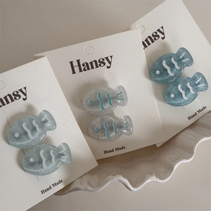 Macro view of blue fish-shaped resin hair clips with glitter and striped patterns