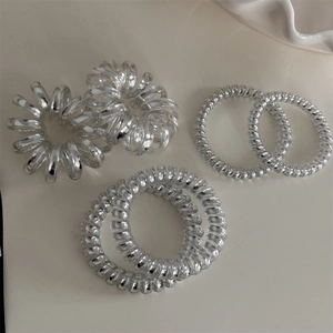 Détail d'élastiques à cheveux spirale argentés montrant le lustre et la texture métal