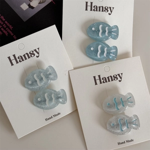 Detailed macro view of handmade fish-shaped hair clips with blue glitter finish