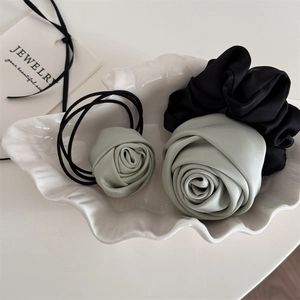 Elegant mint green and black satin rose flower hair scrunchies on a white shell tray