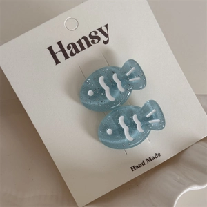 Detail view of cute blue fish hair clips with silver glitter and white wave pattern