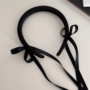 Detail view of the smooth black satin ribbon bows on a minimalist vintage style headband