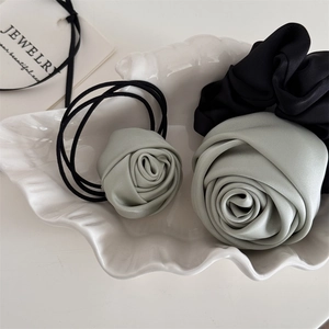 Detail of mint green fabric rose hair scrunchies with satin texture on a shell tray